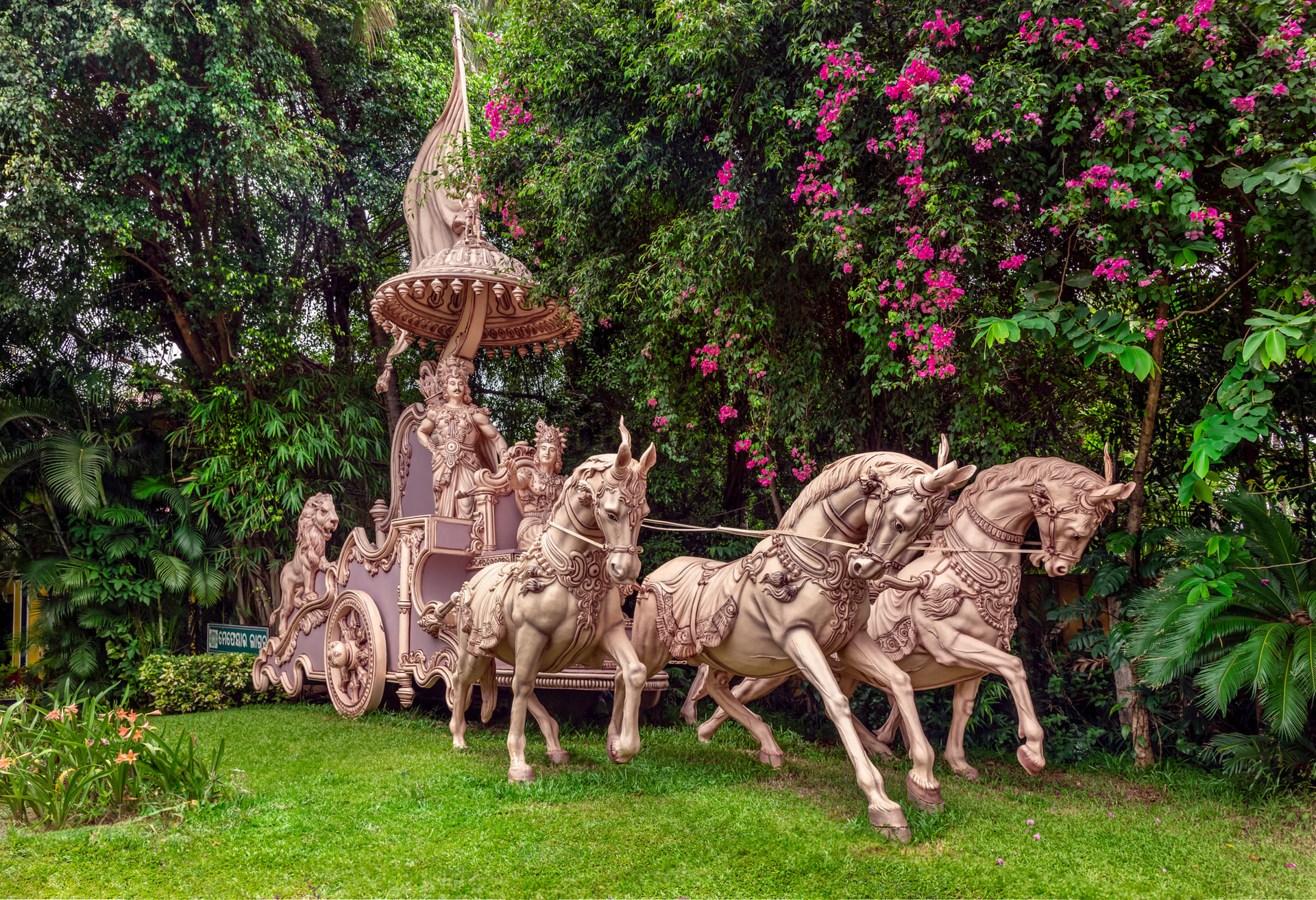 Ornate horse chariot sculpture amidst flowering garden at Mayfair Lagoon, Bhubaneswar