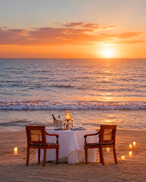 A private candlelit dinner set on the sand at sunset