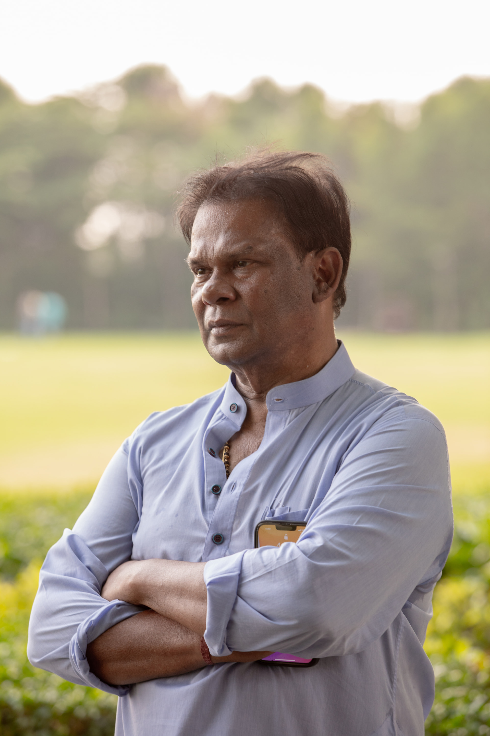 A portrait on the lawn at golden hour, arms folded, the grounds behind