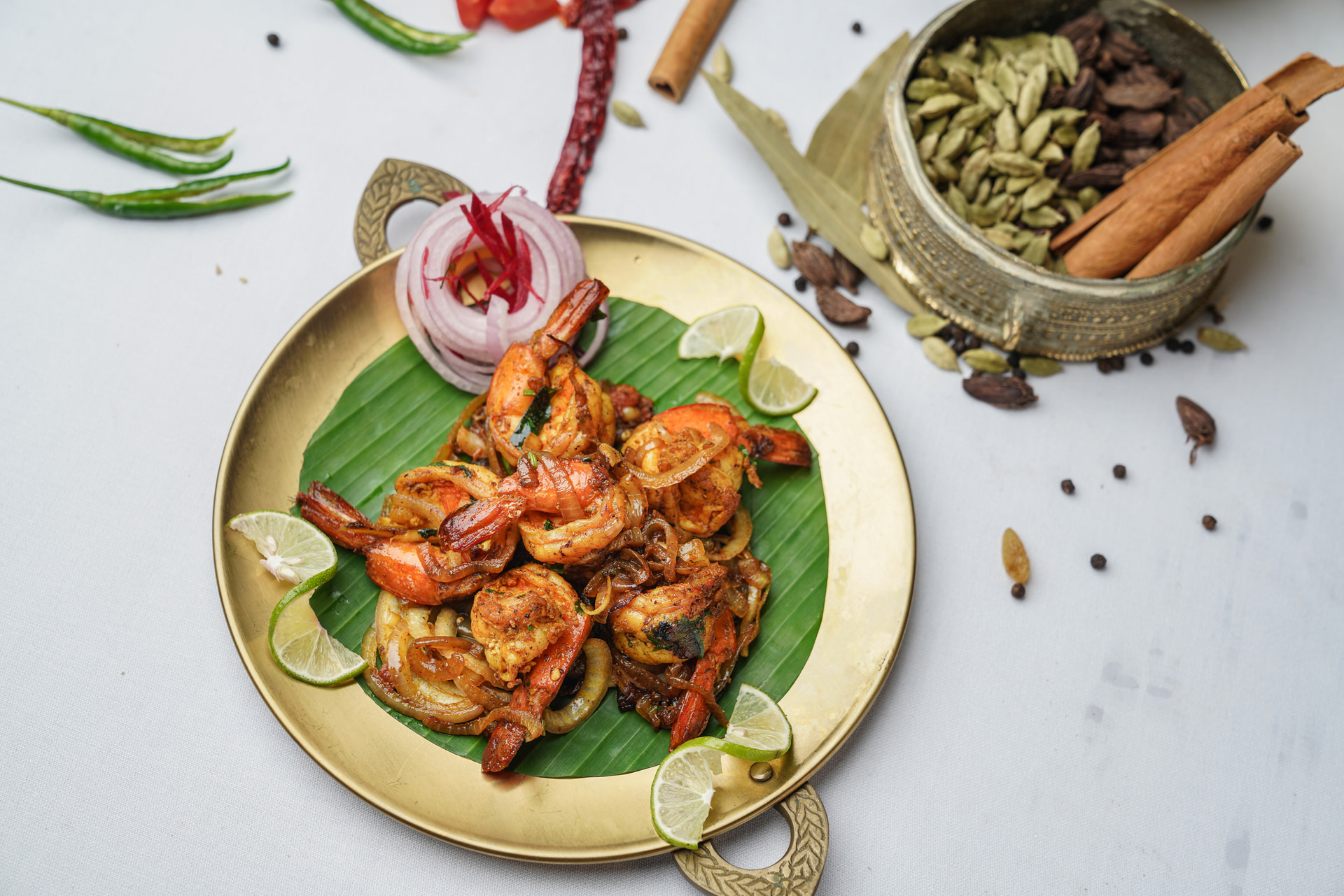 Prawns on a banana leaf with whole spices, from a MAYFAIR kitchen
