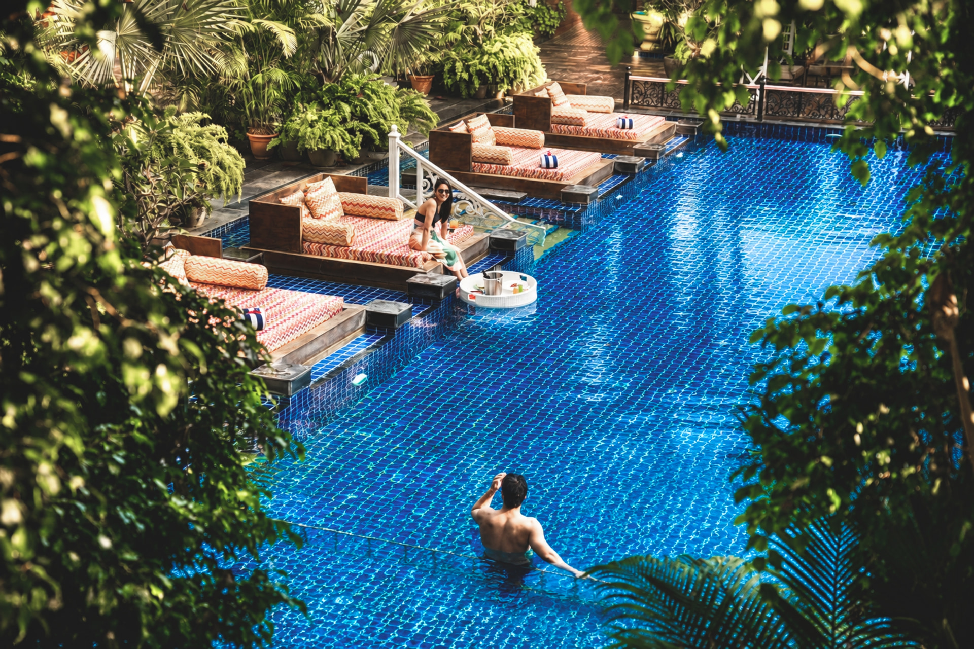 Guests relaxing beside a jade infinity pool framed by tropical foliage