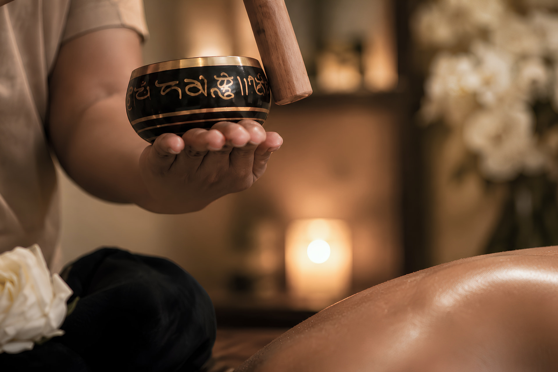 A therapist holding a Tibetan singing bowl during a wellness ritual