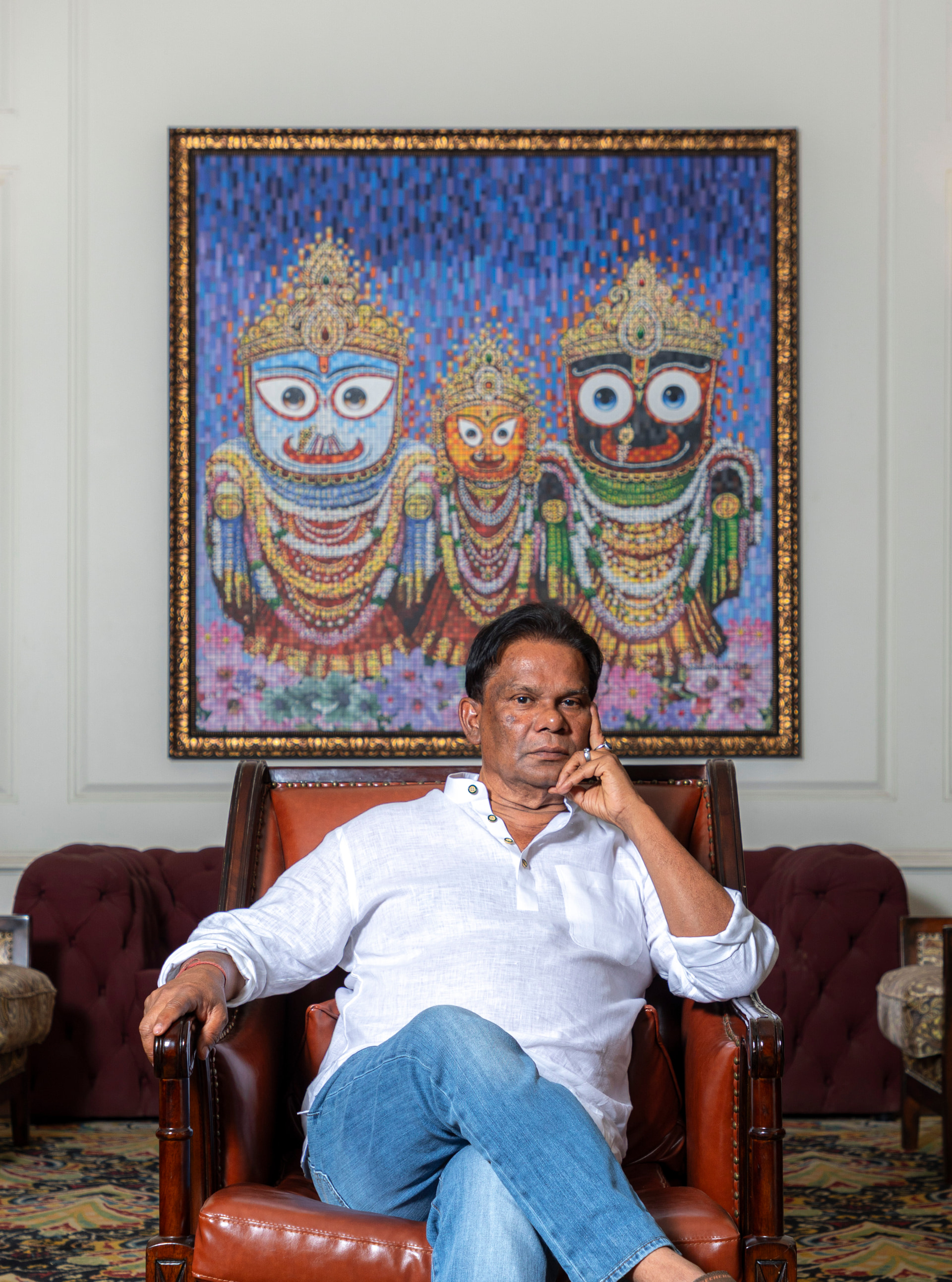 Shri Dilip Ray, founder and chairman of MAYFAIR Hotels & Resorts, seated beneath a pattachitra of Jagannath, Balabhadra and Subhadra