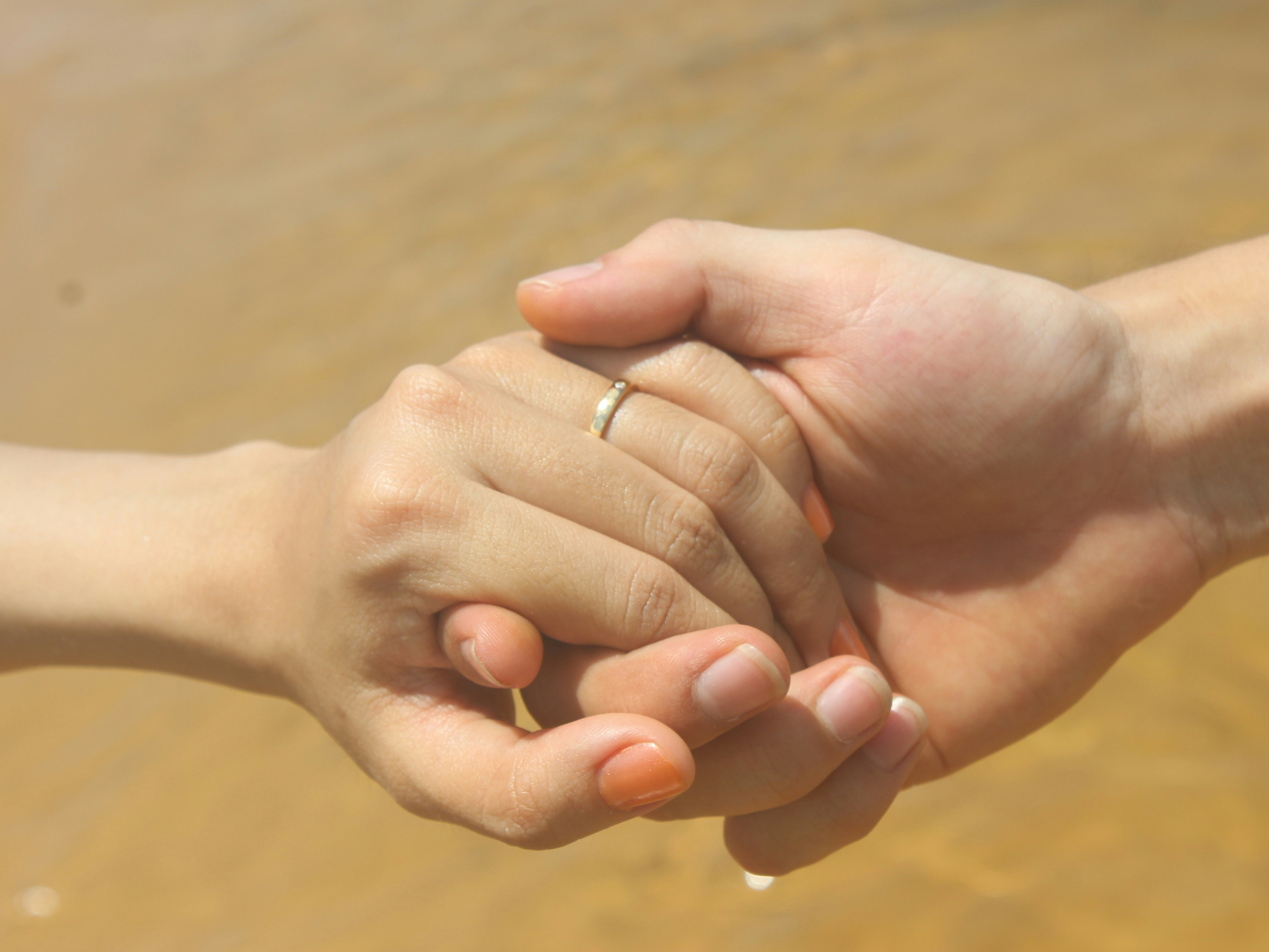 Stock photograph of two clasped hands, one wearing a ring