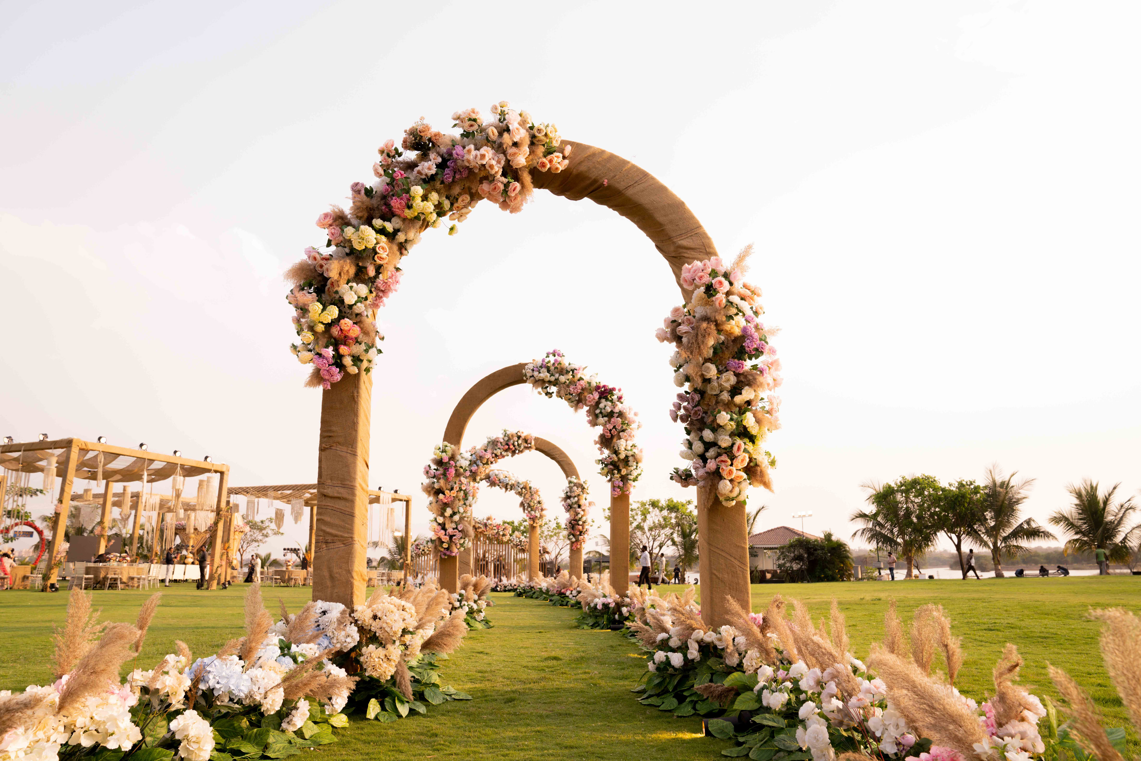 A processional of flower-covered arches across a lawn at a MAYFAIR wedding